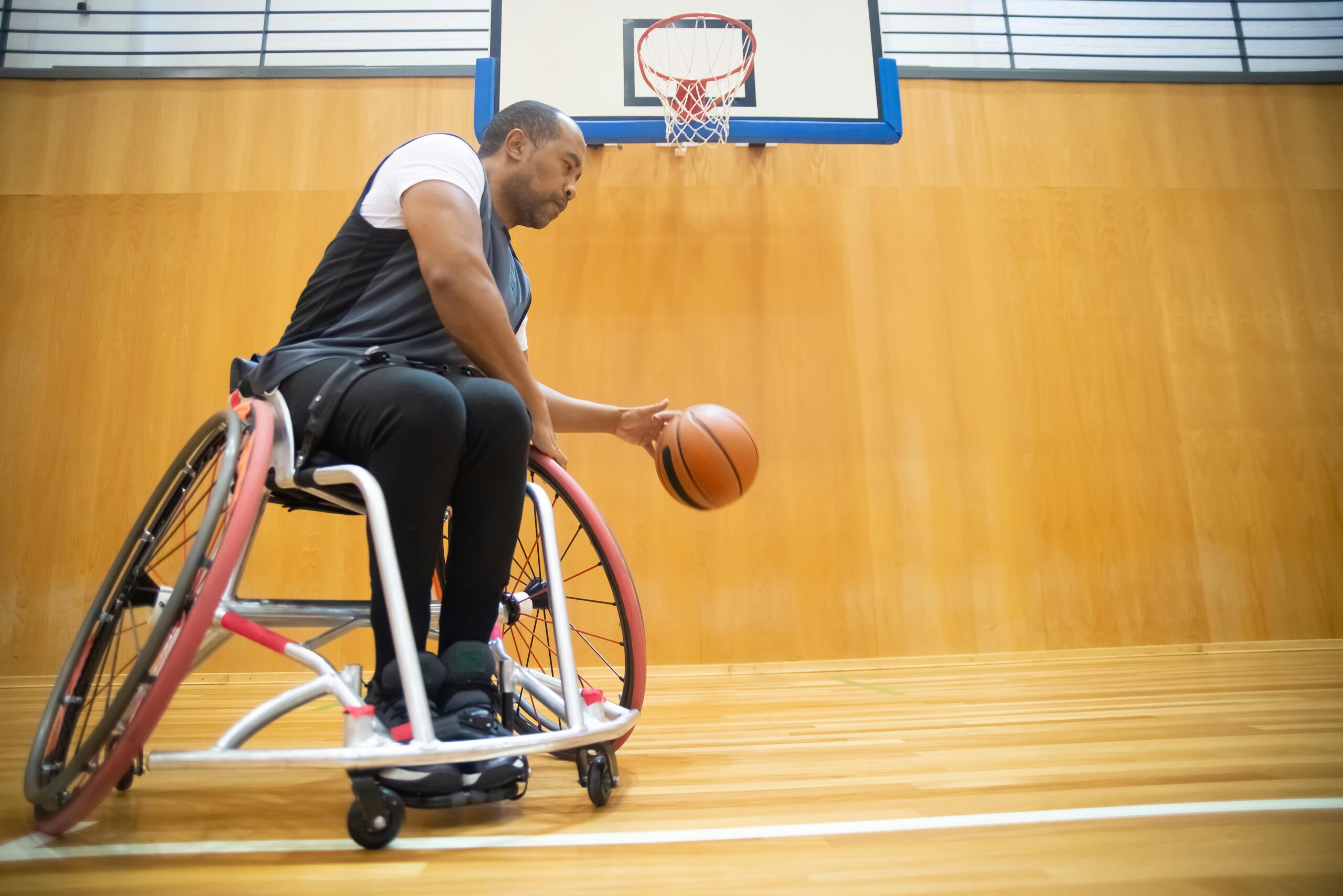 A determined wheelchair basketball player dribbling on a hardwood court, showcasing inclusive sports.